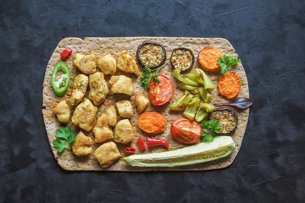 Trozos de filete de pollo frito en pan de tortilla con verduras a la parrilla