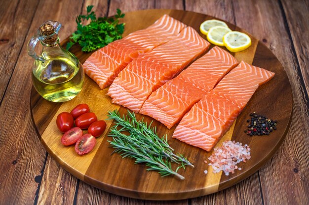 Foto trozos de filete de salmón con especias y aceite de oliva sobre una tabla de madera.