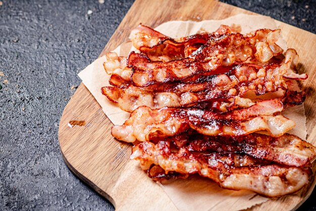 Trozos fragantes de tocino frito en una tabla para cortar