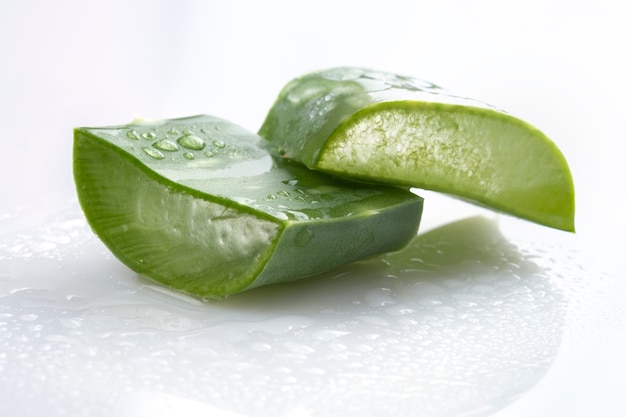 Trozos de hoja de aloe vera con gotas de agua sobre blanco