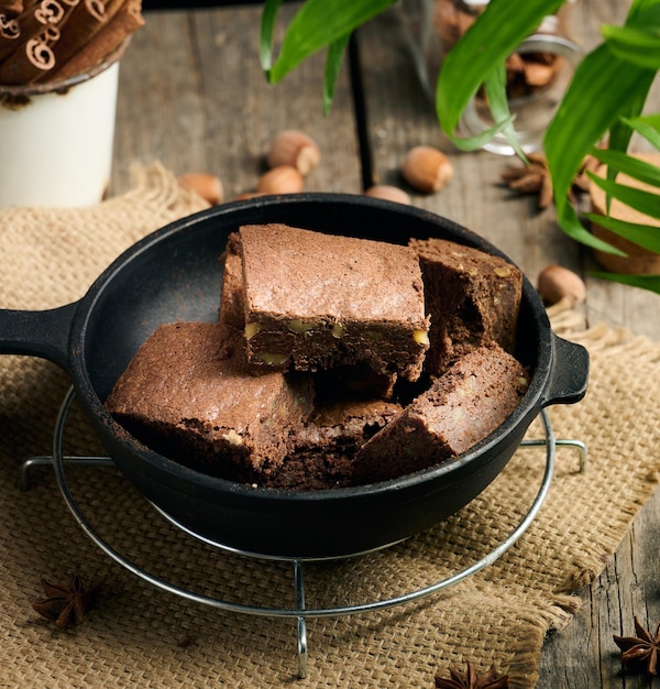 Trozos horneados de pastel de brownie de chocolate con nueces en una sartén de metal negro