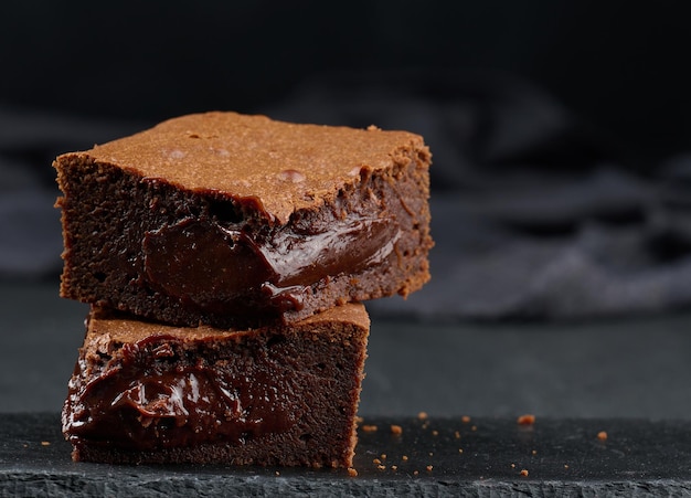 Trozos horneados de pastel de brownie de chocolate en un postre delicioso de mesa negra