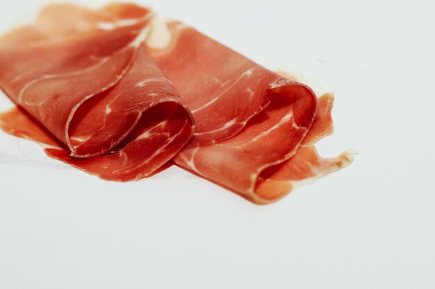 Trozos de jamón de cerdo seco sobre un fondo blanco.