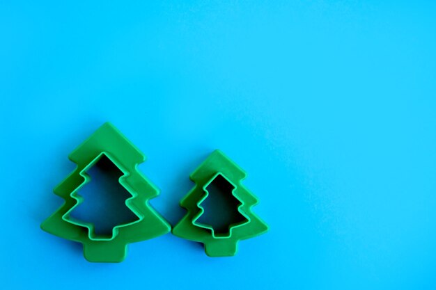 Trozos de masa para galletas Cortador de galletas de árbol de Navidad Paño de pastelería sobre fondo azulVista superior