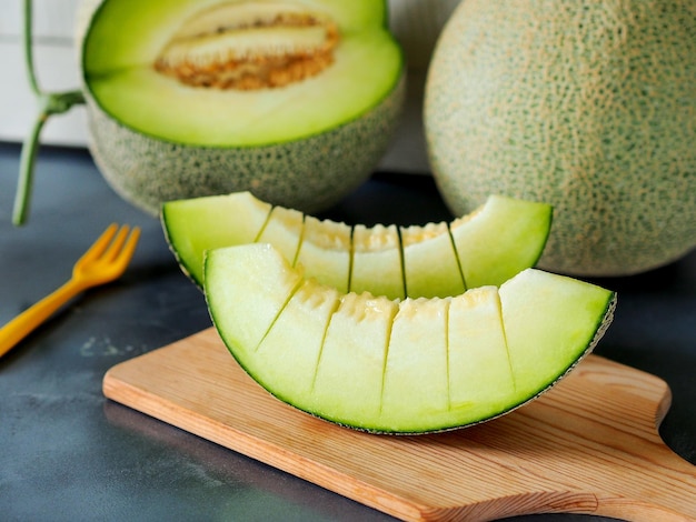 Trozos de melón verde o melón en una tabla de cortar de madera