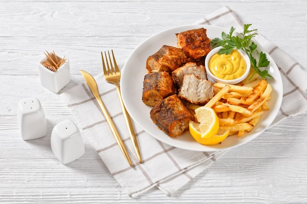 Trozos de merluza frita en un plato con patatas fritas