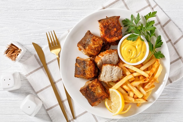 Trozos de merluza frita en un plato con patatas fritas