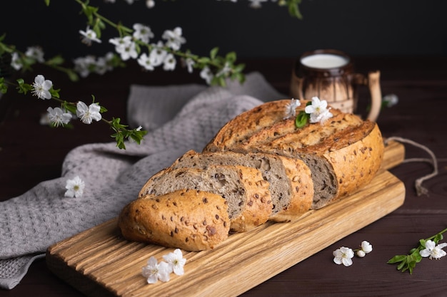 Trozos de pan de centeno casero fresco con taza de arcilla de leche en tabla de cortar de madera Desayuno saludable