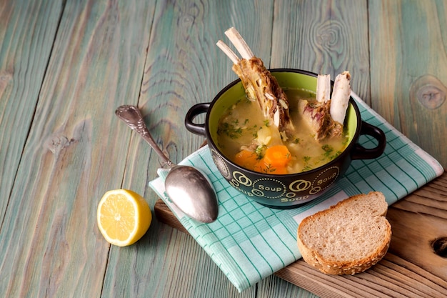 Trozos de pan y deliciosa sopa caliente de oveja en un bol sobre una mesa de madera closeup cocina griega