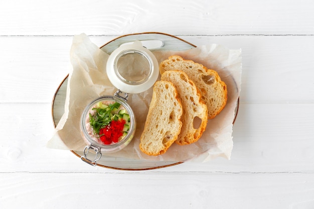 Trozos de pan con paté de pescado sobre mesa de madera blanca