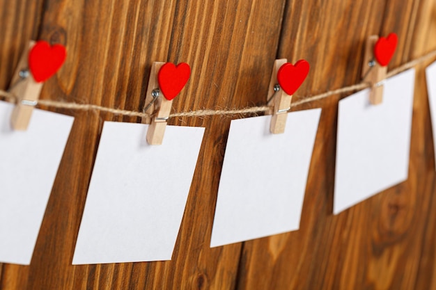 Trozos de papel blanco sobre pinzas para la ropa con un corazón sobre un fondo de madera