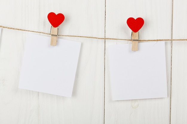 Trozos de papel blanco sobre pinzas para la ropa con un corazón sobre un fondo de madera