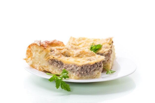 Trozos de pastel de carne cocida en un plato aislado sobre un fondo blanco.