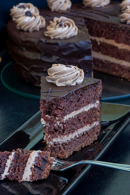Foto trozos de pastel de chocolate casero en capas con plato blanco de crema de hielo enfoque selectivo cerrar