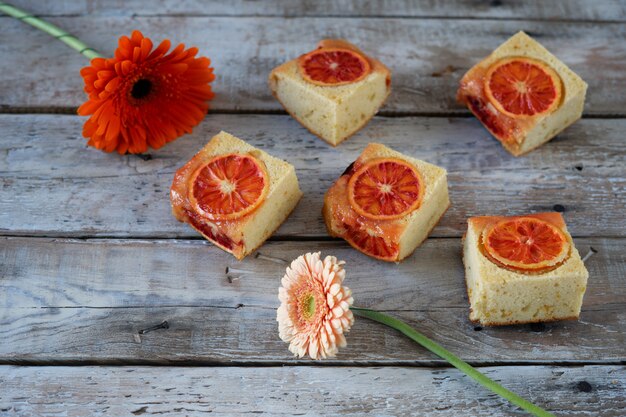 Trozos de pastel con naranja de sangre y dos flores.