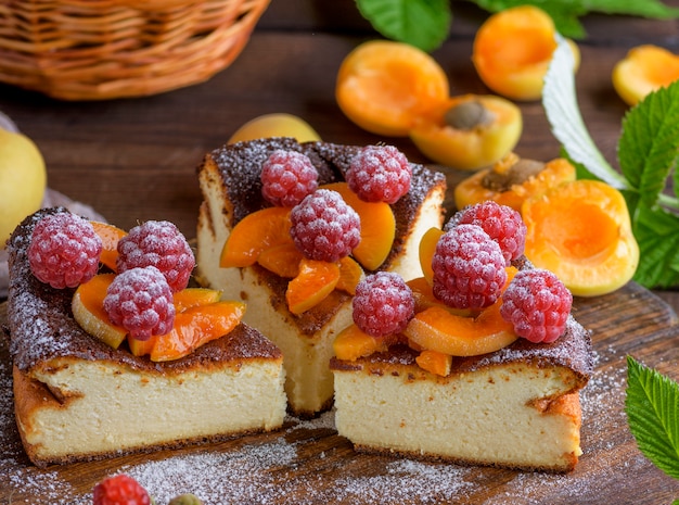 Trozos de pastel de requesón con fresas y albaricoques.