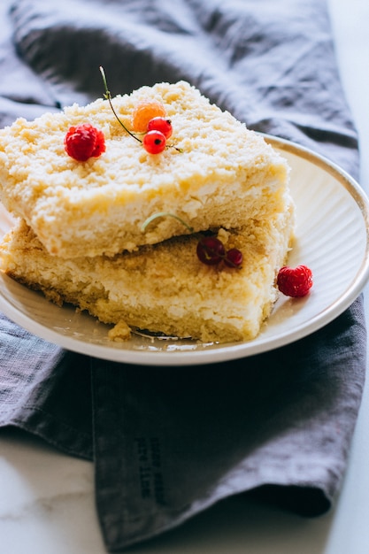 Trozos de pastel de requesón con una migaja decorada con frambuesas y grosellas rojas