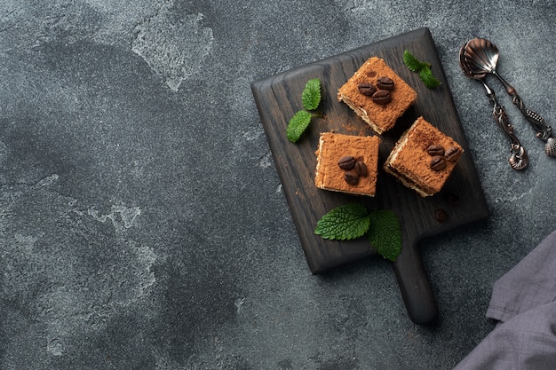 Trozos de pastel de tiramisú con crema delicada, granos de café y hojas de menta. Vista superior.