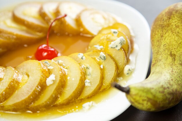 Trozos de pera en almíbar de naranja con queso Dorblu en un plato blanco