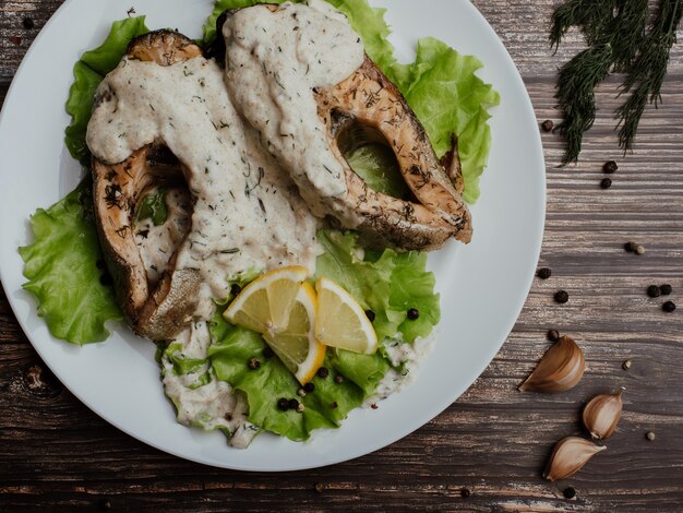 Trozos de pescado rojo frito con salsa de crema en un plato blanco