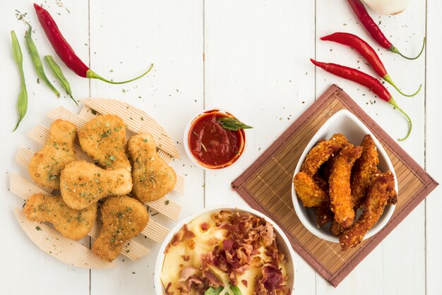 Trozos de pollo y nuggets con pimiento picante en mesa de madera