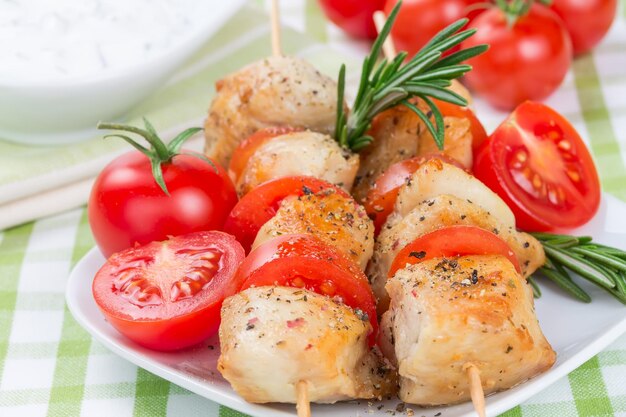 Trozos de pollo a la parrilla en brochetas con tomates