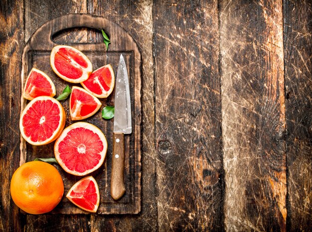 Trozos de pomelo en rodajas con un cuchillo.