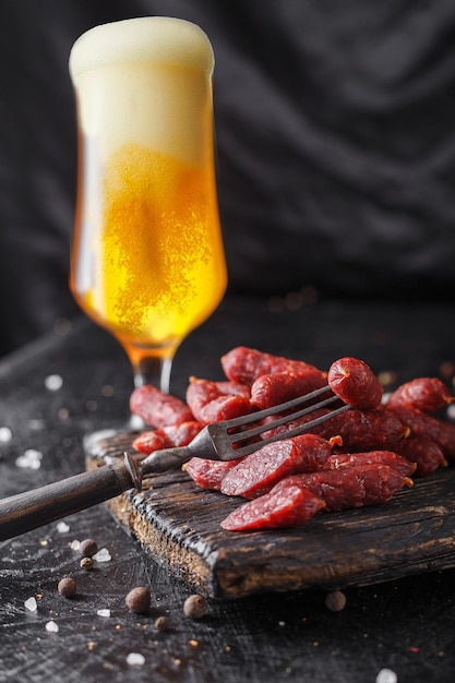 Foto trozos de queso en un plato mini salchichas salami ahumado palos tabla de cortar de madera gafas con be