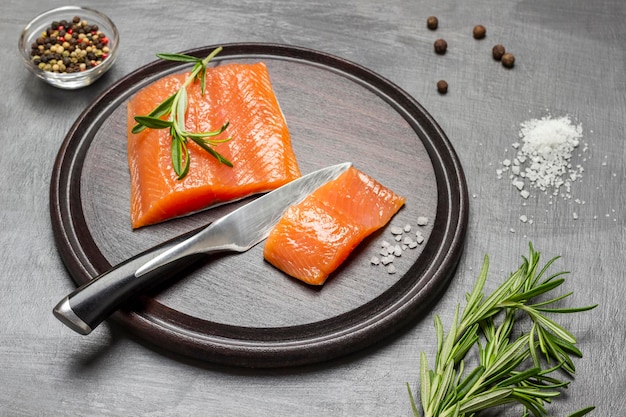 Trozos de salmón y cuchillo de cocina en tabla de cortar