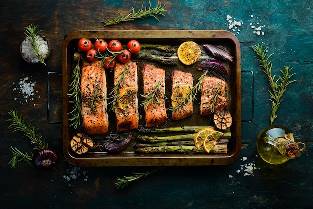 Trozos de salmón a la parrilla en una bandeja de metal con verduras y romero. Receta. Mariscos. Espacio libre para texto.