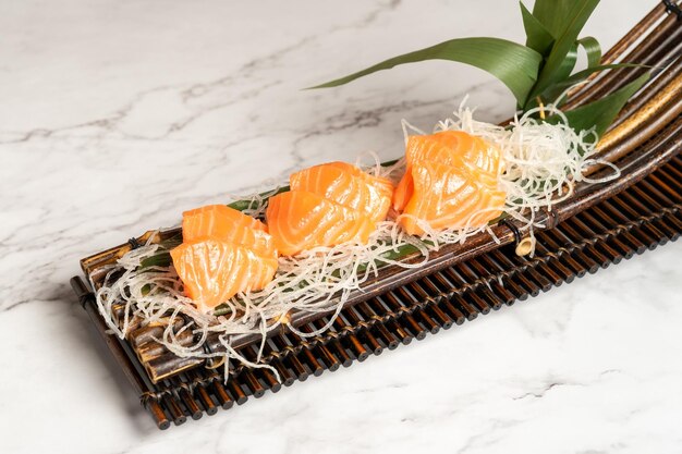 Trozos de salmón presentados en un plato curvo de bambú.