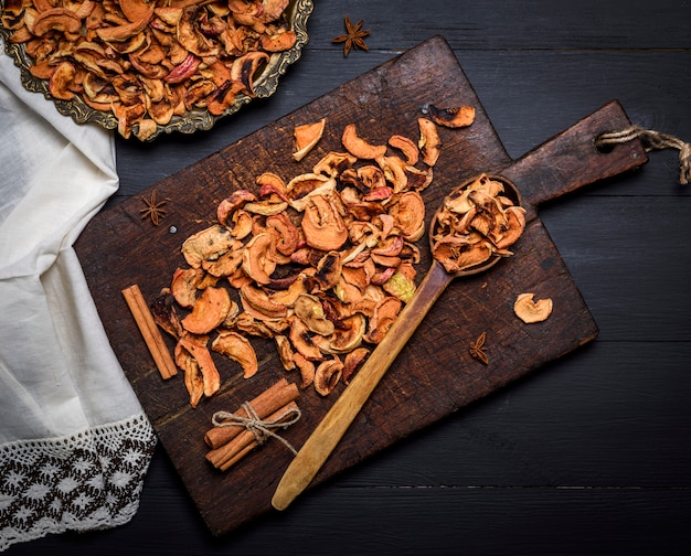 Trozos secos de manzanas en una placa de hierro y en una tabla de madera marrón