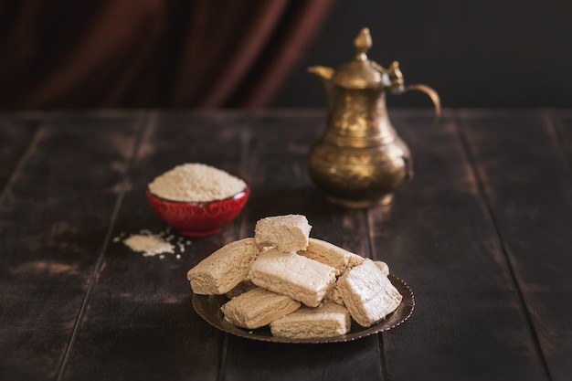 Trozos de tahini halva, semillas de sésamo en un bol, una jarra vintage