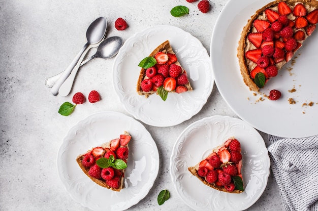 Trozos de tarta de bayas con frambuesas, fresas y crema.