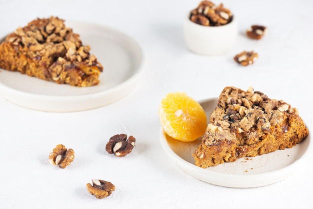 Trozos de tarta casera de mandarina con nueces en platos sobre una mesa de luz