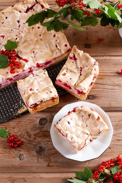 Trozos de tarta de grosella casera dulce en un plato con grosella roja en la mesa de madera