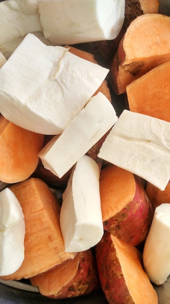 trozos de yuca blanca y trozos de camote rojo anaranjado, listos para hervir en la estufa.