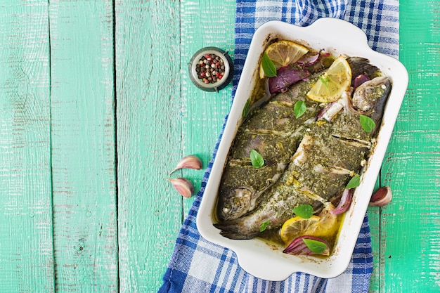 Trucha al horno y ensalada fresca sobre un fondo de madera brillante