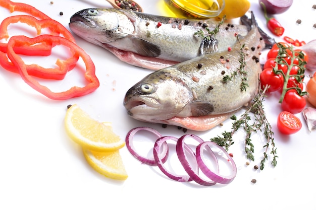 Trucha de pescado con especias y verduras sobre un fondo blanco.