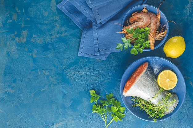 Trucha pescado rodeado de perejil, limón, camarones, gambas en plato de cerámica