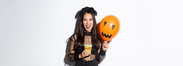 Foto truco o trato de bruja aterrador en halloween con dulces y globo naranja de pie en encaje gótico