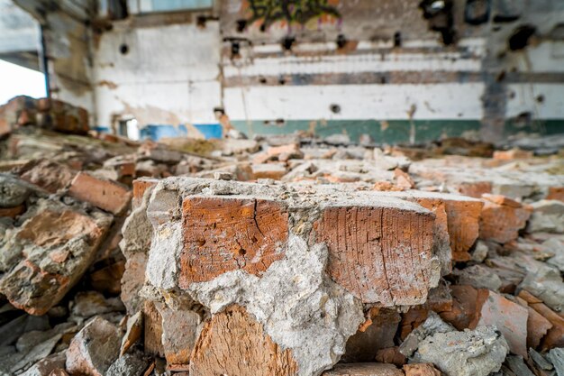 Trümmer von Ziegeln in den Ruinen des zerstörten Fabrikgebäudes im Inneren Steinstücke bröckeln von abgerissenen Wänden eines Hauses Nahaufnahme