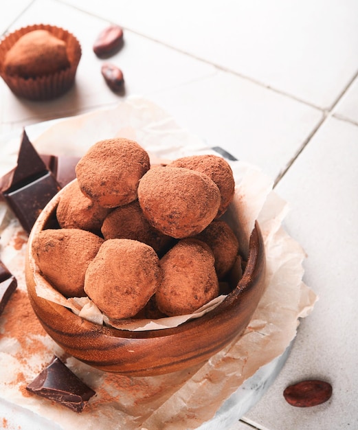 Trufas de chocolate con cacao en polvo en un plato de madera sobre un viejo fondo de mesa de azulejos agrietados Sabrosas trufas de chocolate dulces Concepto del Día de San Valentín y el Día de la Madre con espacio de copia Vista superior