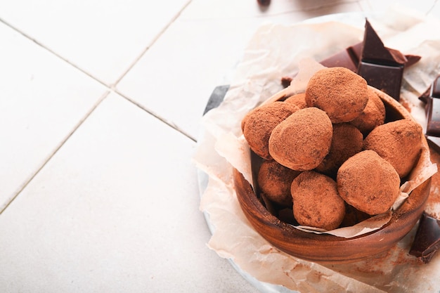 Trufas de chocolate con cacao en polvo en un plato de madera sobre un viejo fondo de mesa de azulejos agrietados Sabrosas trufas de chocolate dulces Concepto del Día de San Valentín y el Día de la Madre con espacio de copia Vista superior