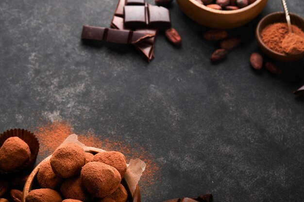 Trufas de chocolate con cacao en polvo en un plato de madera sobre un viejo fondo de mesa de hormigón oscuro Sabrosas trufas de chocolate dulces dulces Concepto del Día de San Valentín y el Día de la Madre con espacio de copia Vista superior