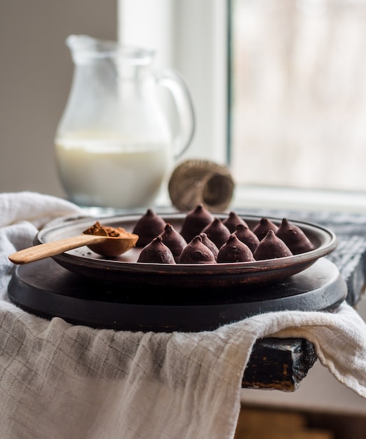 Trufas de chocolate dulces en un plato de crema oscura y en una jarra