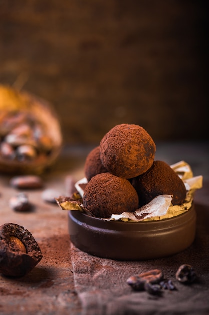 Trufas de chocolate hechas en casa en la opinión de primer plano de la tabla de madera. Sabrosos dulces vegetarianos o bolas con cacao en polvo crudo