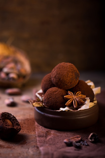 Trufas de chocolate hechas en casa en la opinión de primer plano de la tabla de madera. Sabrosos dulces vegetarianos o bolas con cacao en polvo crudo
