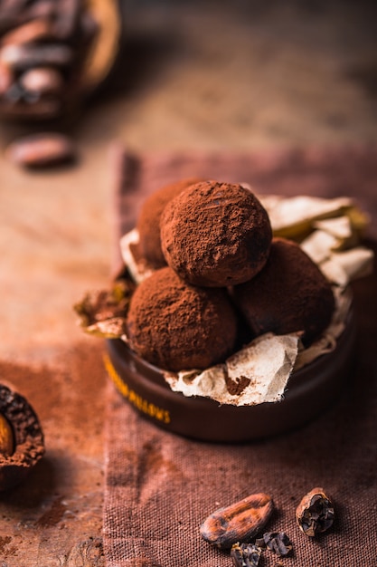 Trufas de chocolate caseiros na opinião de madeira do close up da tabela. Saborosos doces vegetarianos ou bolas com cacau em pó cru
