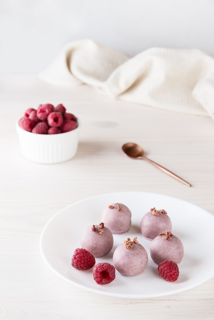 Trufas de framboesa em chocolate rosa em um prato branco sem glúten e lactose